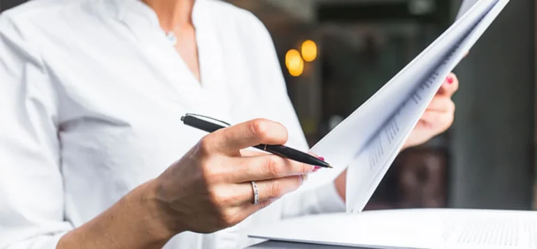 Mulher em traje executivo folheando páginas impressas: registro de logomarca