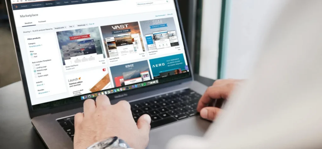 A imagem mostra a tela de um laptop aberto com uma página de marketplace de templates para sites. É um passo importante durante o processo de registro de domínio, para que você personalize seu site após finalizar o registro.